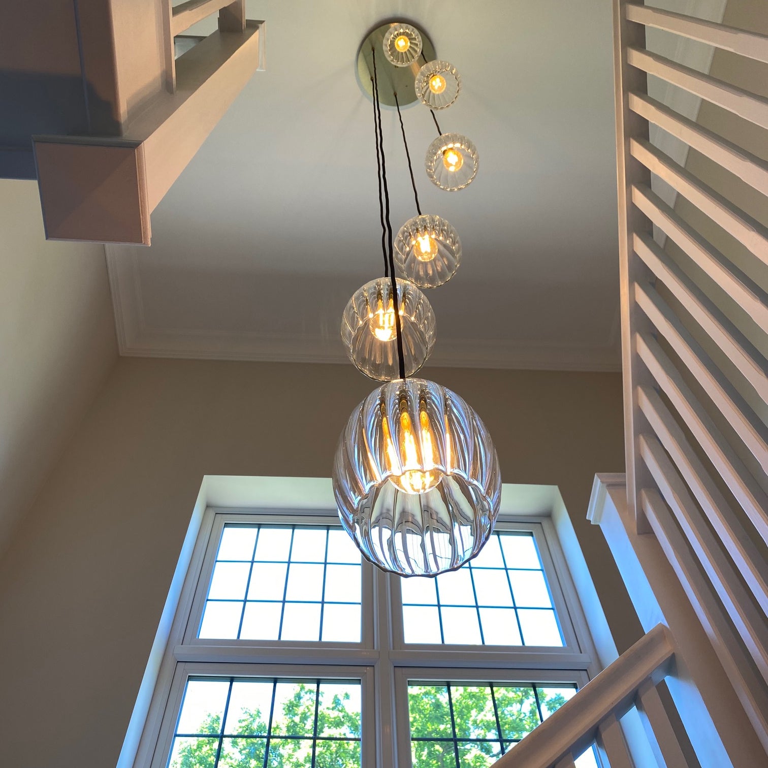 Clear ribbed glass staggered pendant cluster light enhances beautiful staircase