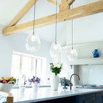3 ribbed glass pendant lights hanging over a kitchen island in a modern barn conversion home
