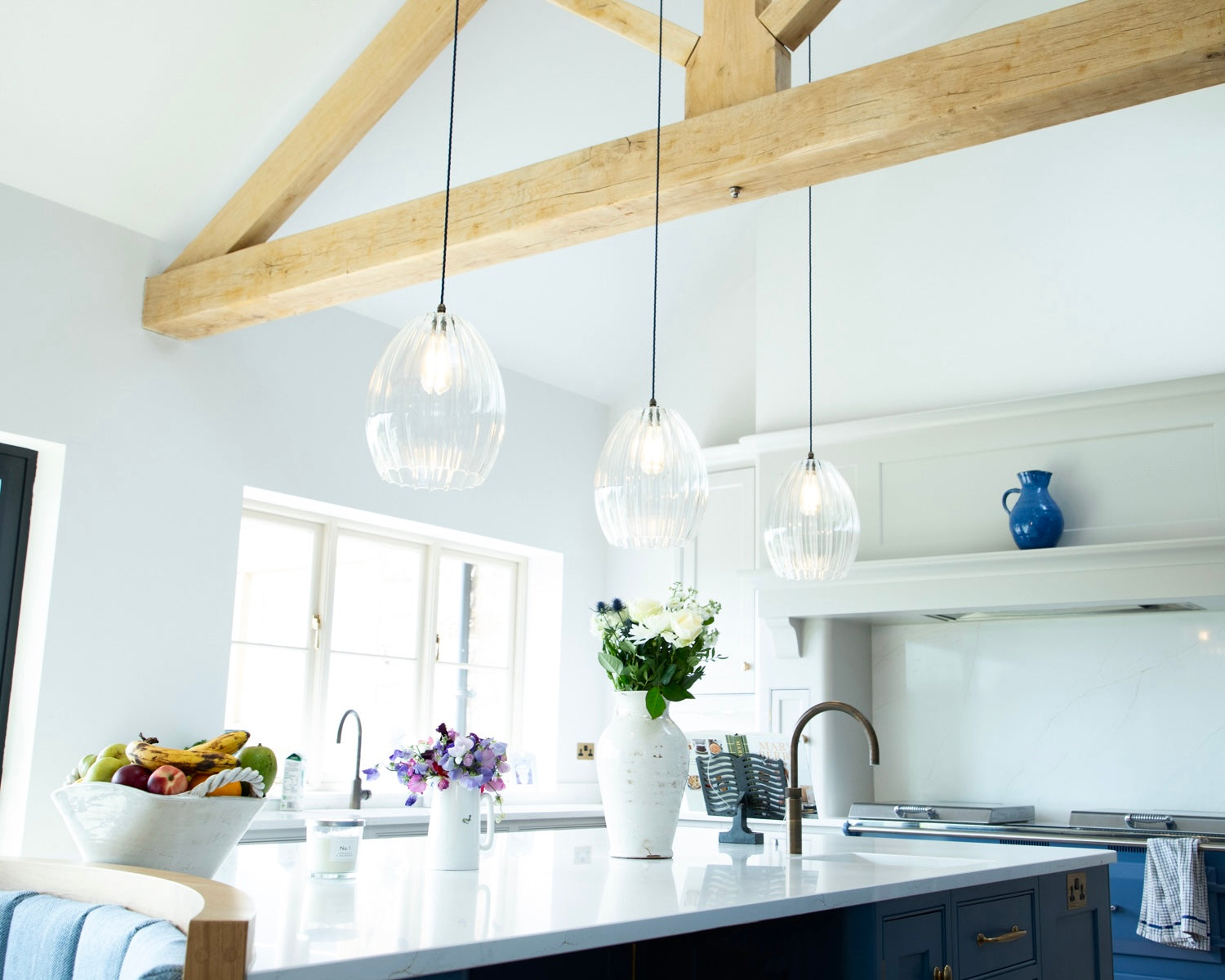 3 ribbed glass pendant lights hanging over a kitchen island in a modern barn conversion home