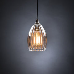 Medium ribbed glass pendant light featuring an illuminated bulb and black cable.