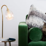 Ribbed table lamp featuring gold stand and marble based. Styled on a side table with green velvet sofa.