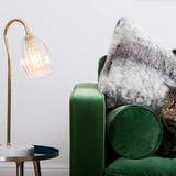 Ribbed table lamp featuring gold stand and marble based. Styled on a side table with green velvet sofa.