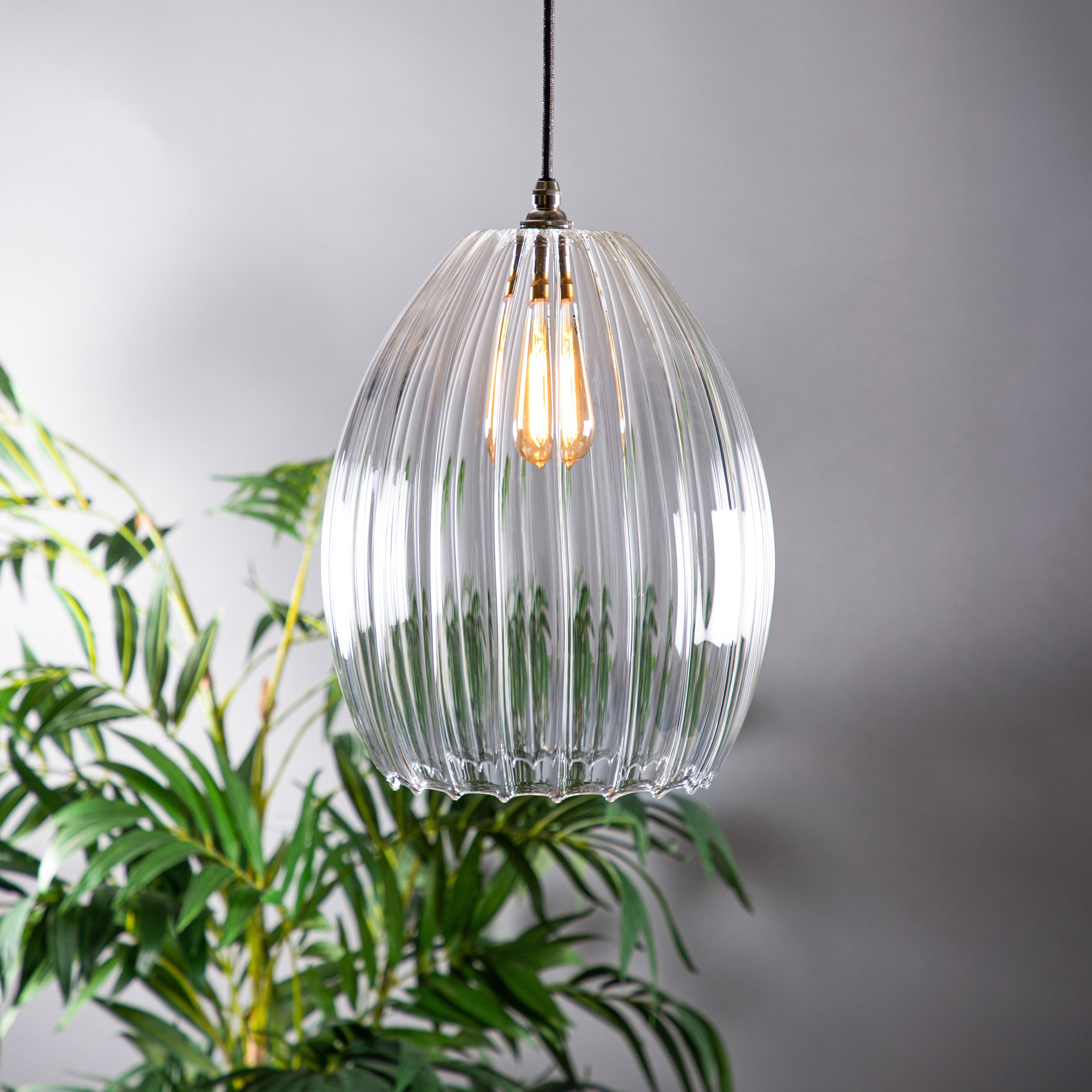 Large ribbed glass pendant light featuring an antique style bulb and old english style fittings.