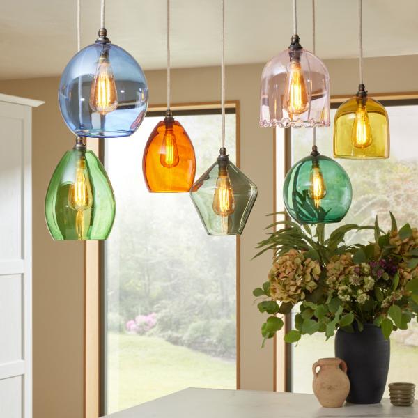 Selection of 7 coloured glass pendant lights hanging at different lengths in varying shapes and colours