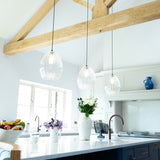 3 ribbed glass pendant lights hanging over a kitchen island in a modern barn conversion home