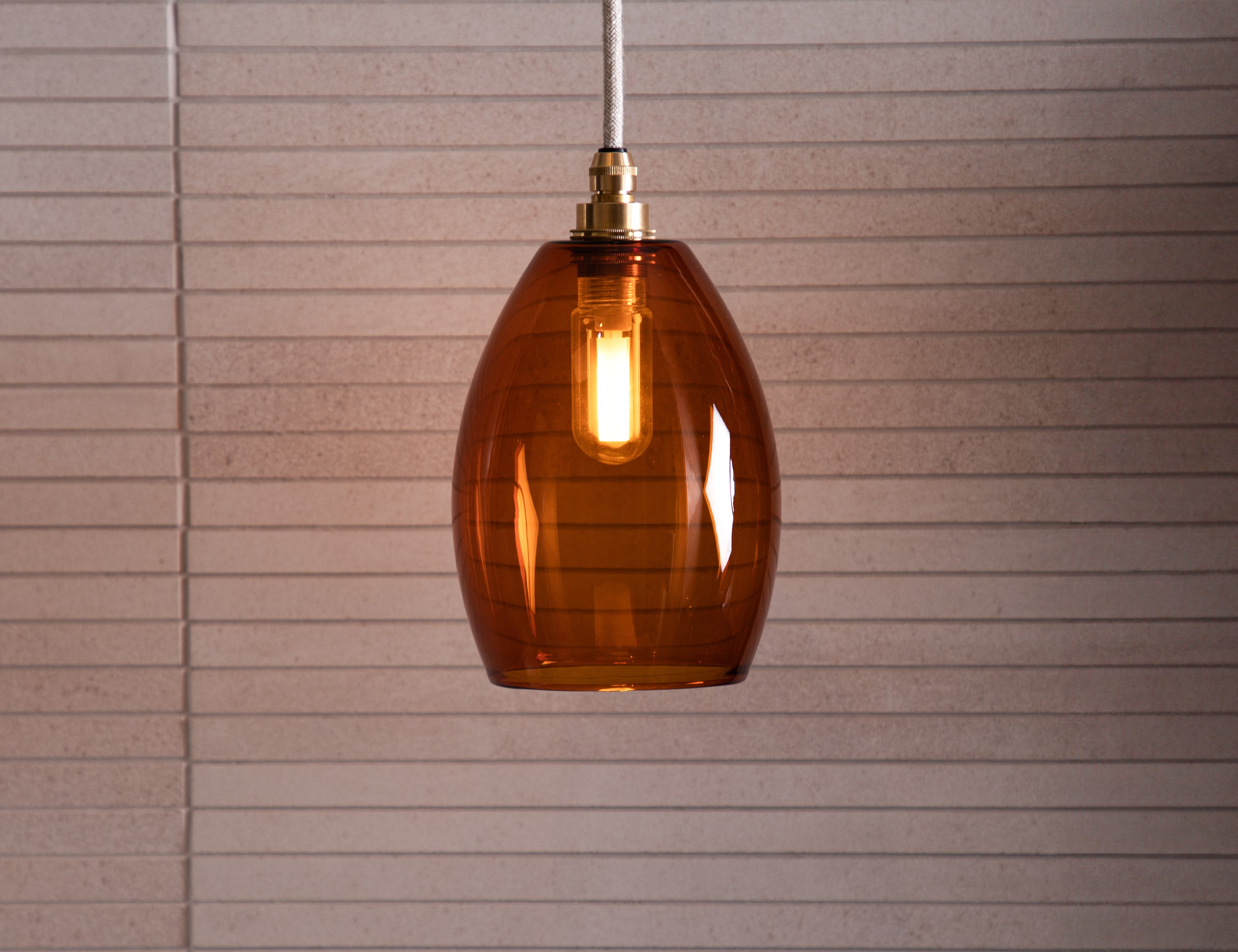 Large glass amber pendant light in a neutral bathroom setting