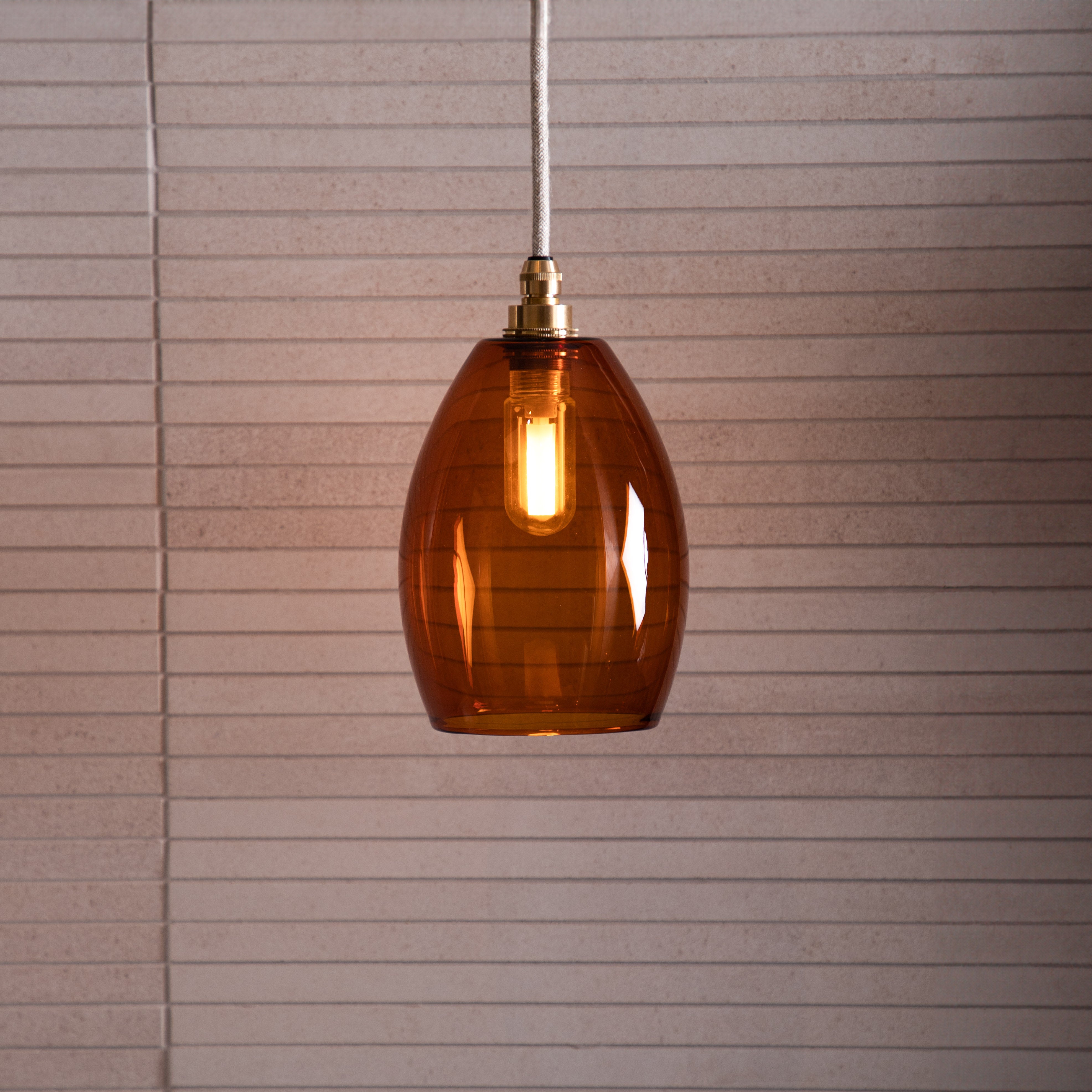 Large glass amber pendant light in a neutral bathroom setting