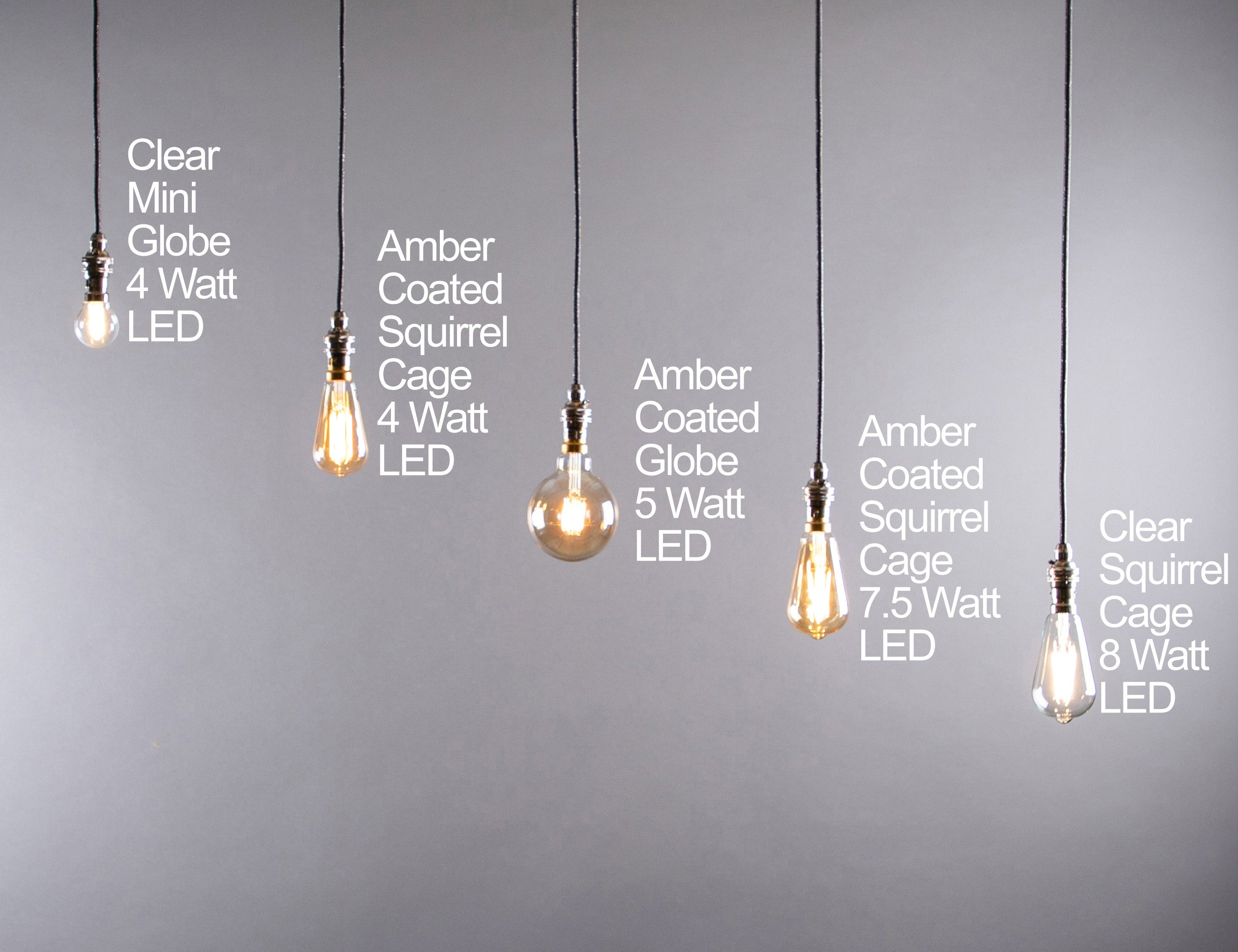 A display showing various LED dimmable light bulbs with B22 base, hanging from the ceiling in a row, with both clear and amber colored glass options.