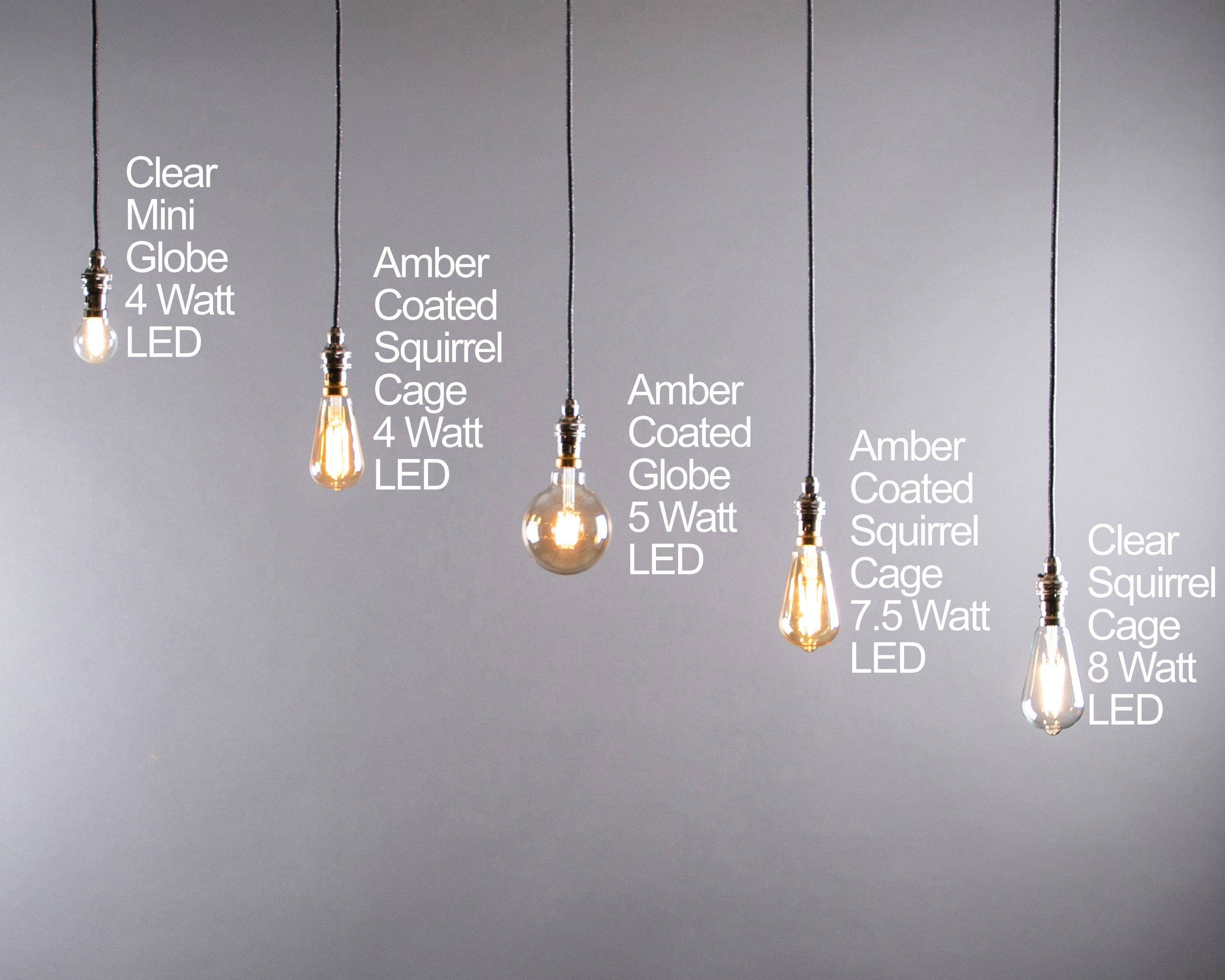 A display showing various LED dimmable light bulbs with B22 base, hanging from the ceiling in a row, with both clear and amber colored glass options.