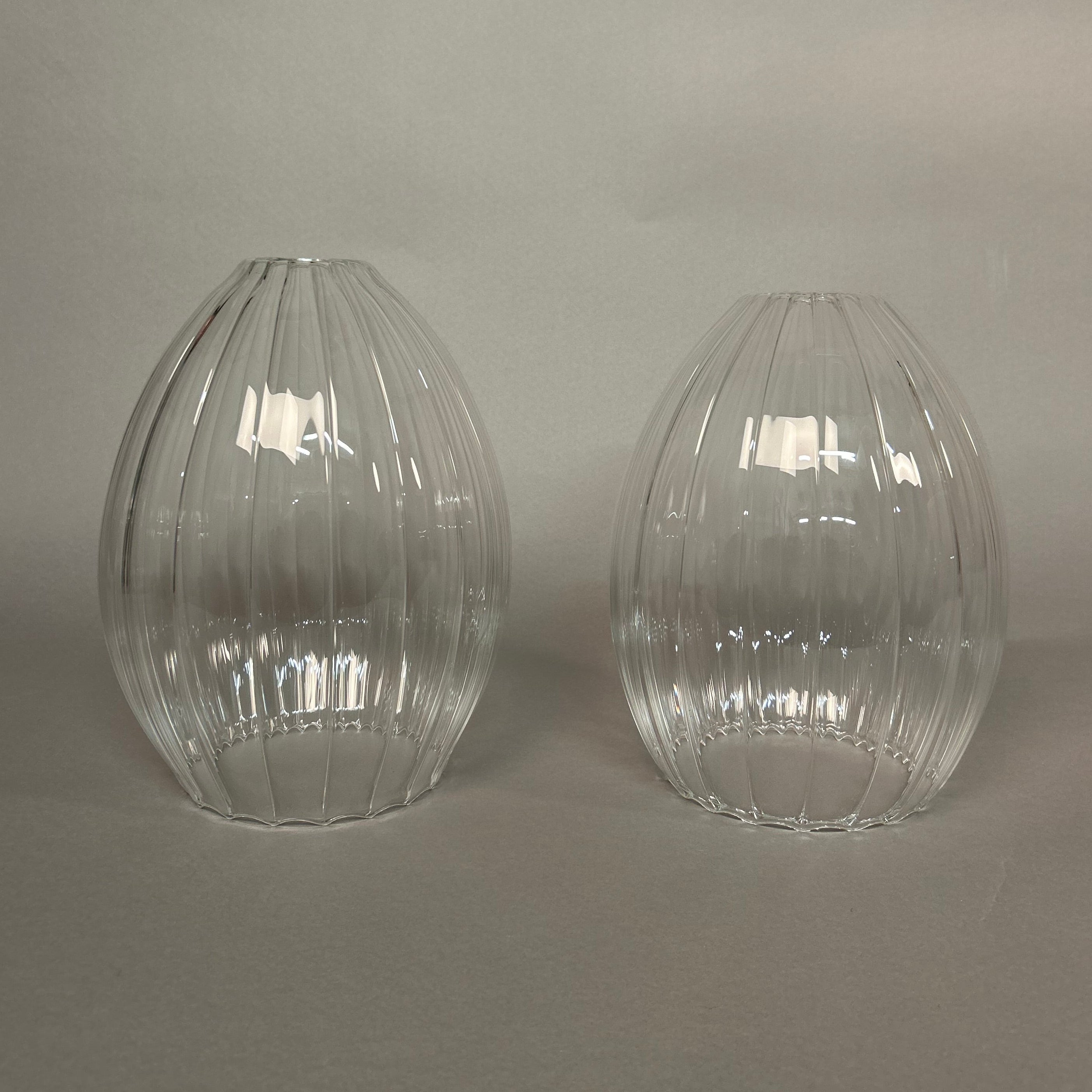 Two clear glass pendant lights with ribbed texture on a light grey background