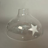 Clear glass pendant light with star designs on a grey background