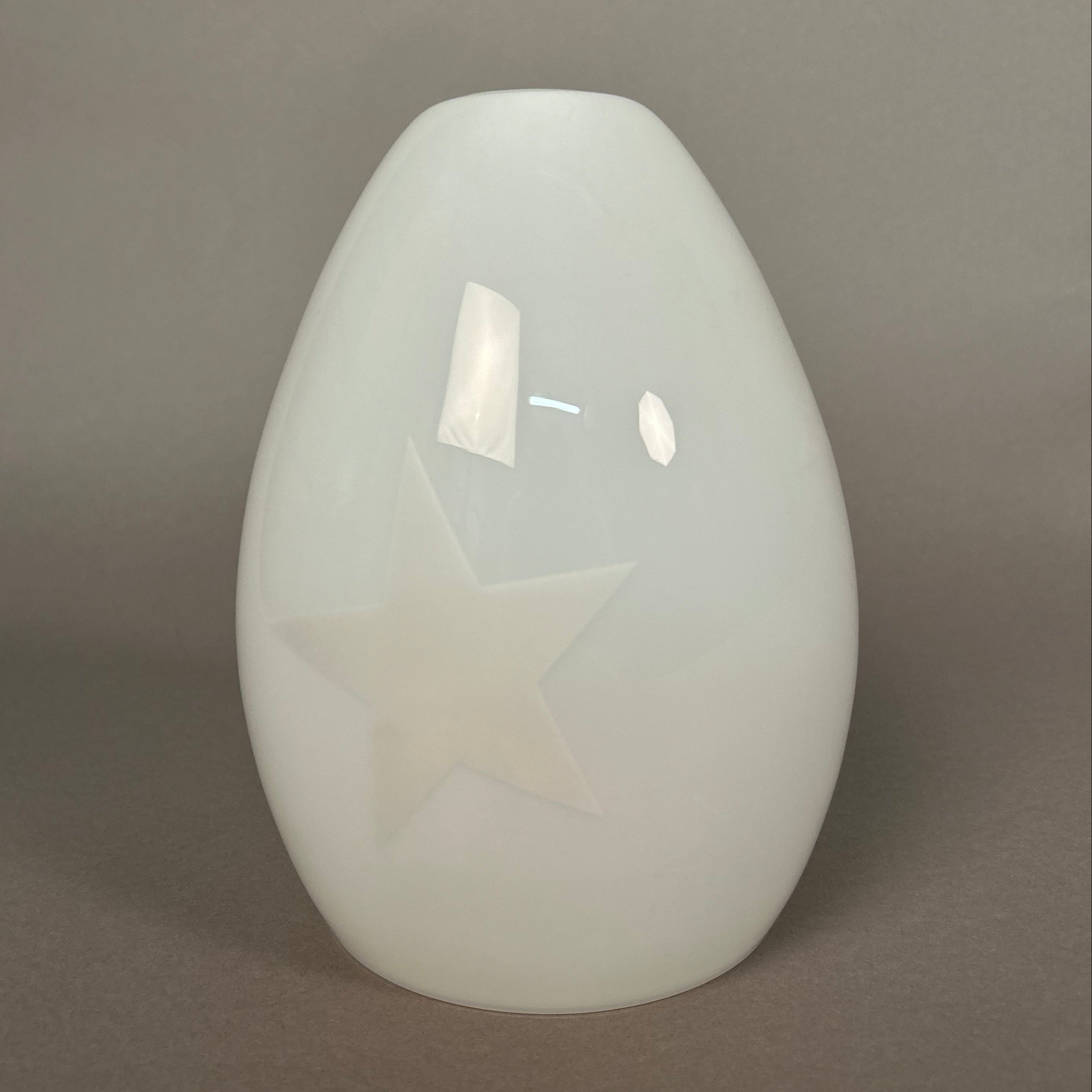 White glass pendant ceiling light fixture on a grey wall