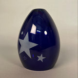 Blue glass light with star patterns on a light grey background