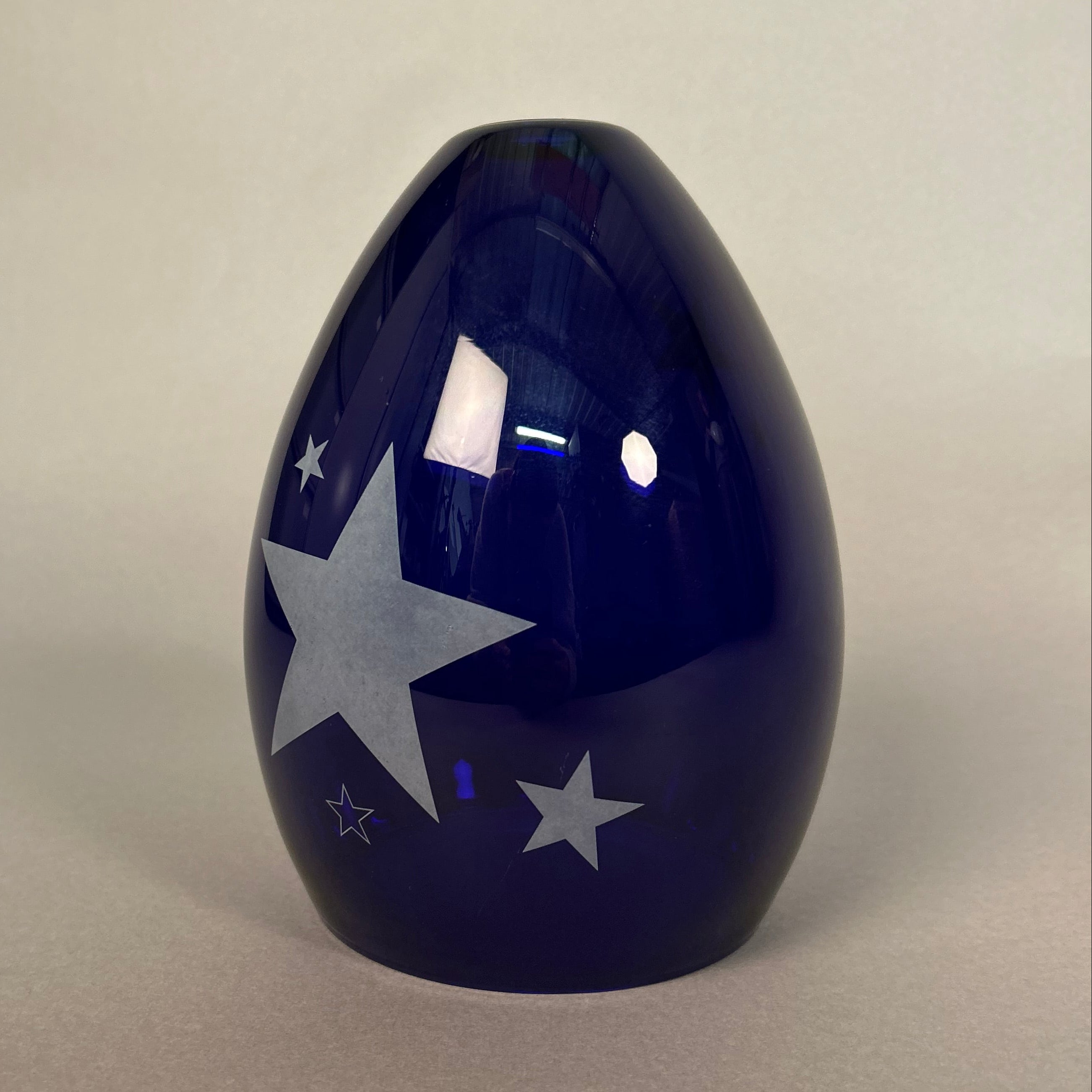 Blue glass light with star patterns on a light grey background