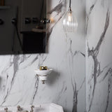 Marble bathroom featuring a small ribbed pendant light