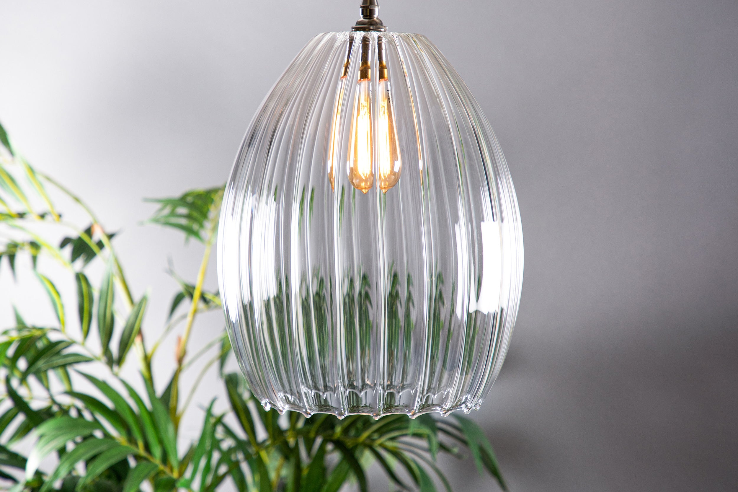 Large ribbed glass pendant light featuring an antique style bulb and old english style fittings. 