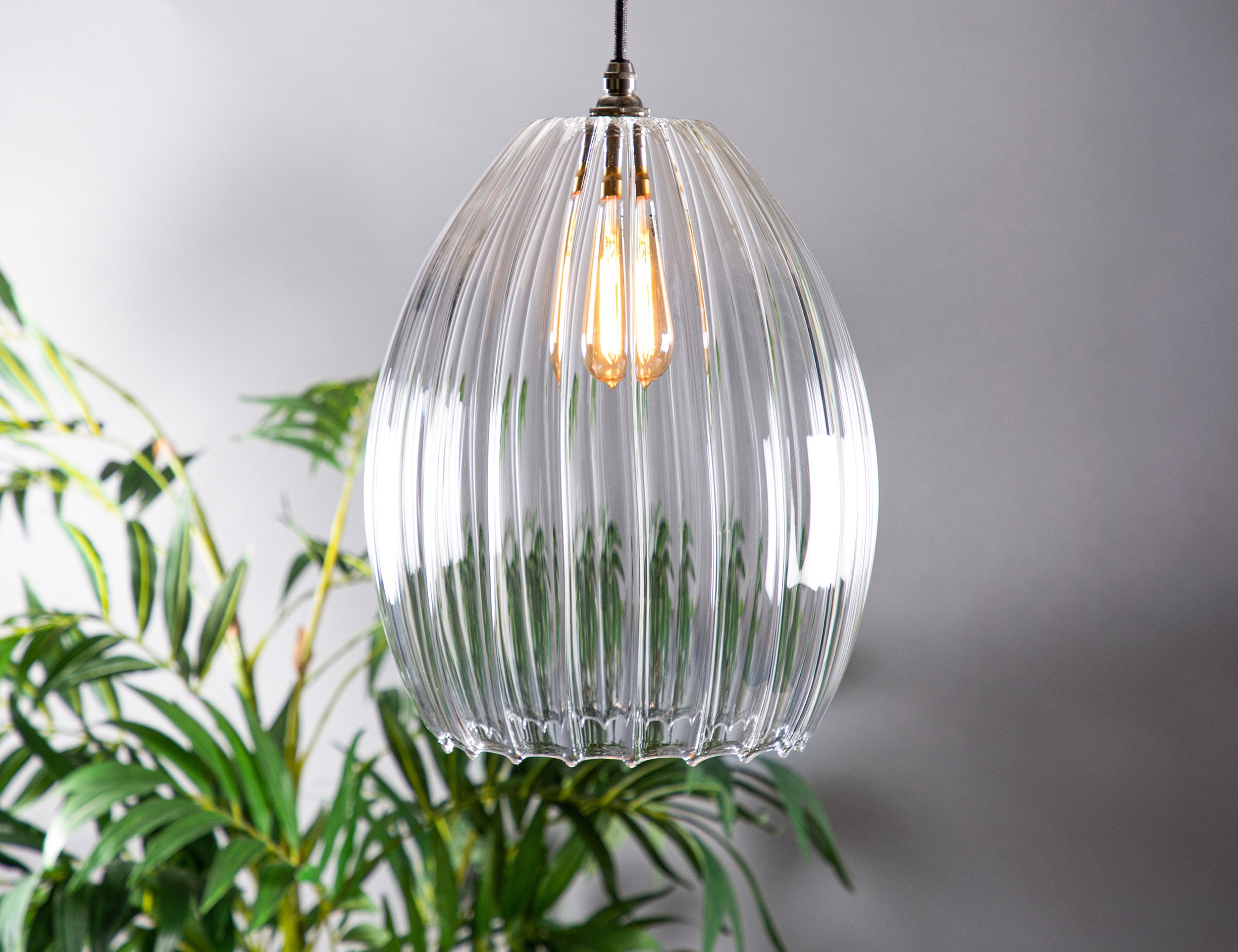 Large ribbed glass pendant light featuring an antique style bulb and old english style fittings. 